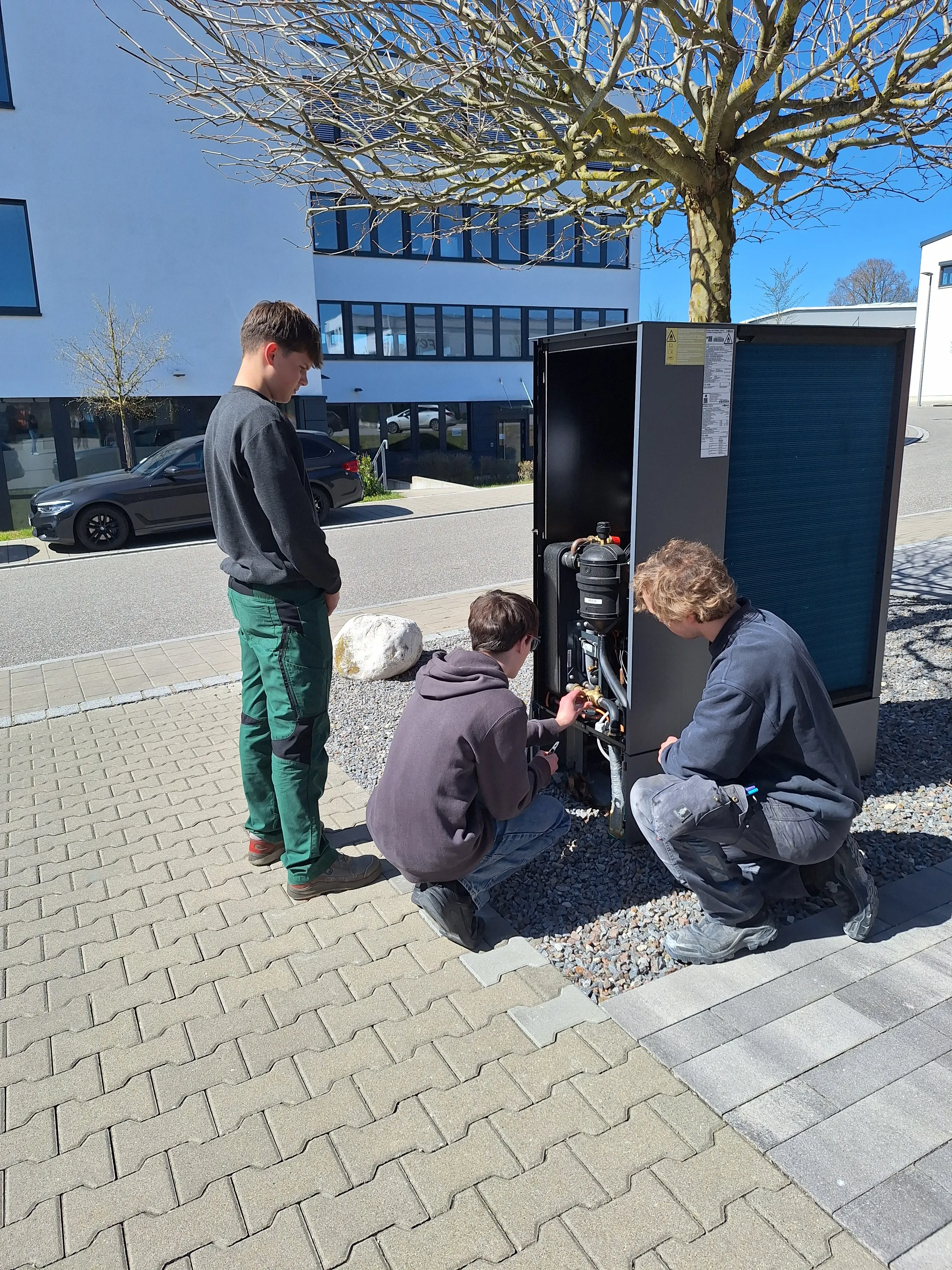 3 Personen arbeiten an einer Wärmepumpe 