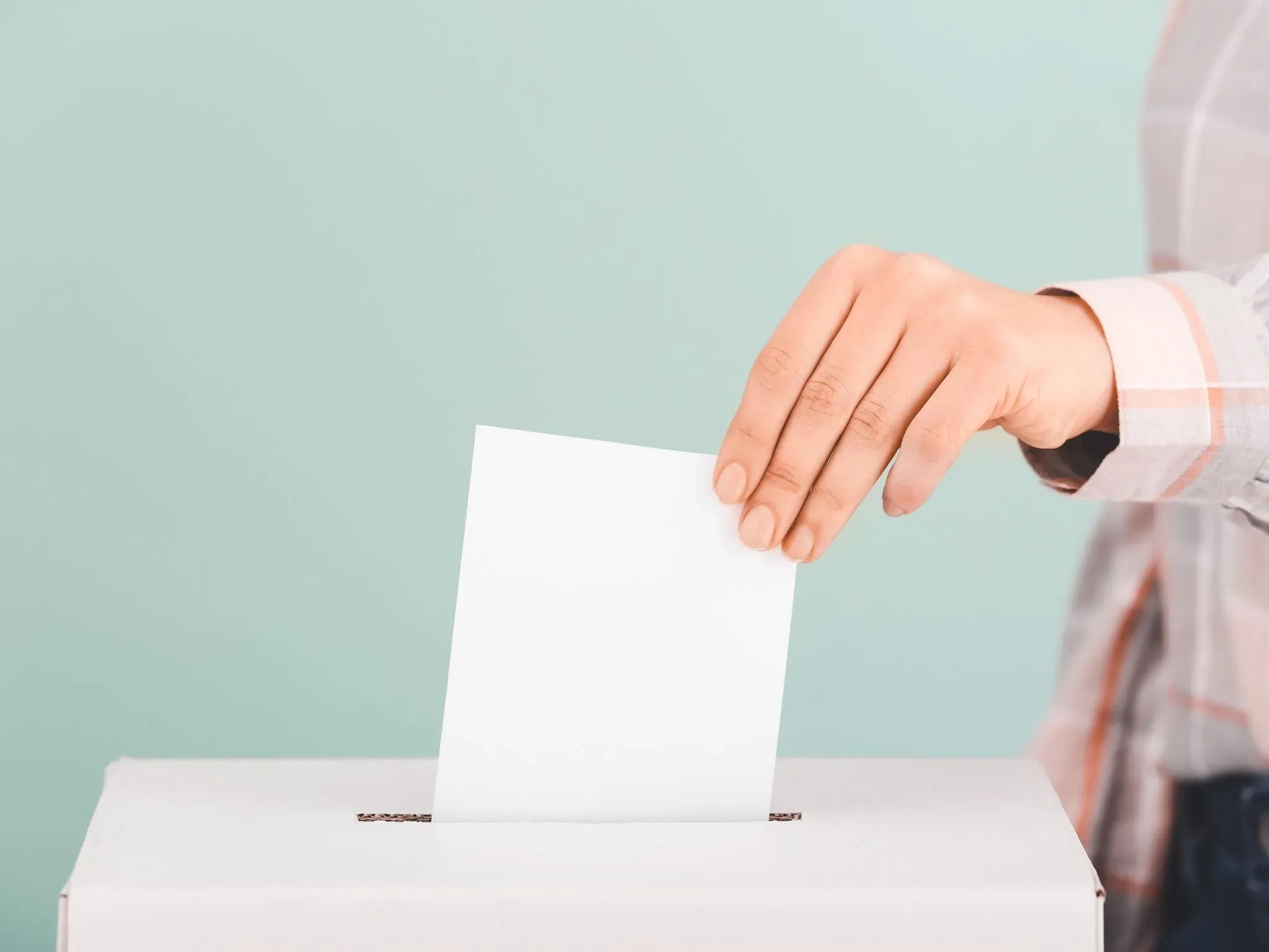 Stimmzettel wird in Wahlurne eingeworfen