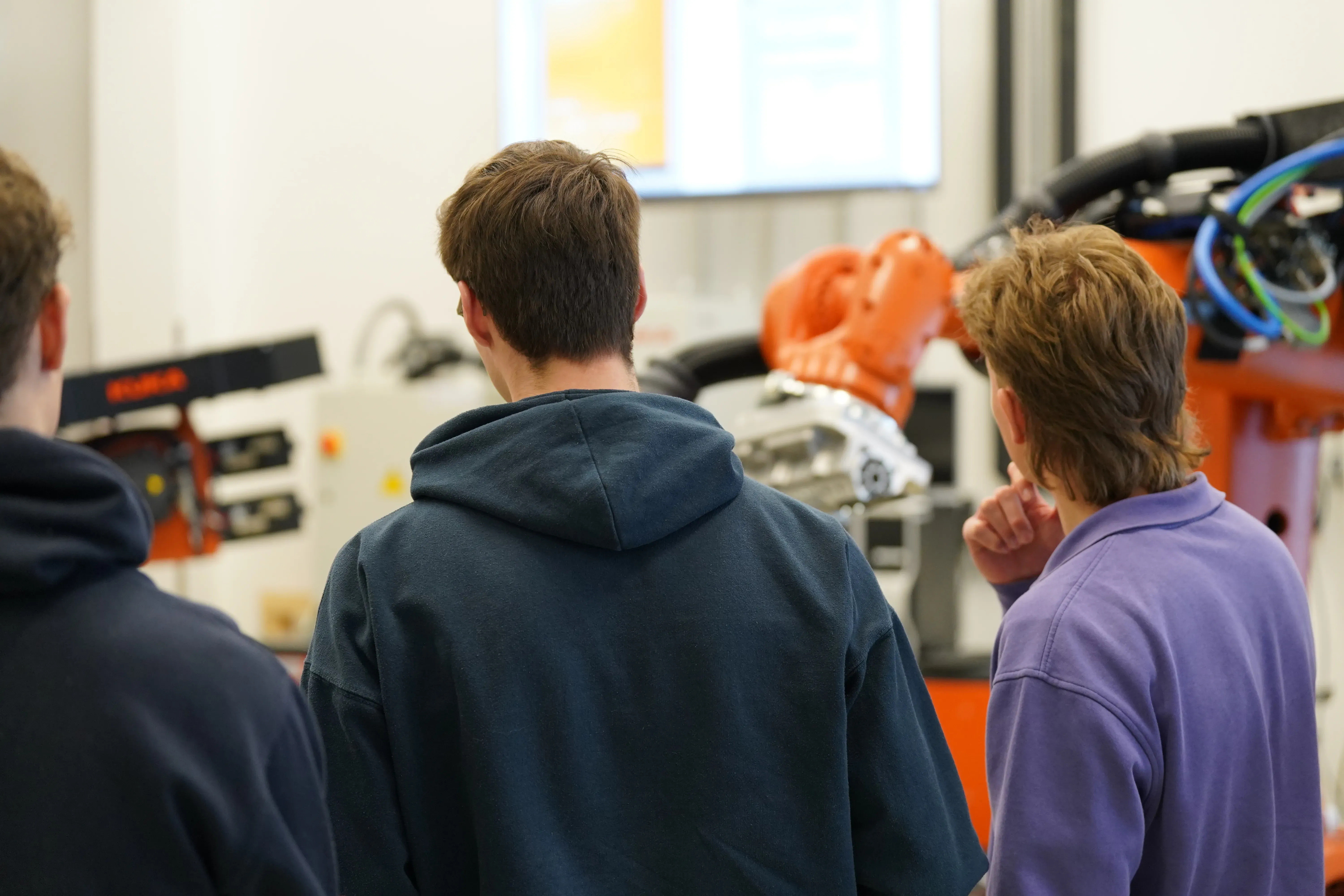 3 menschen vor einem Roboter