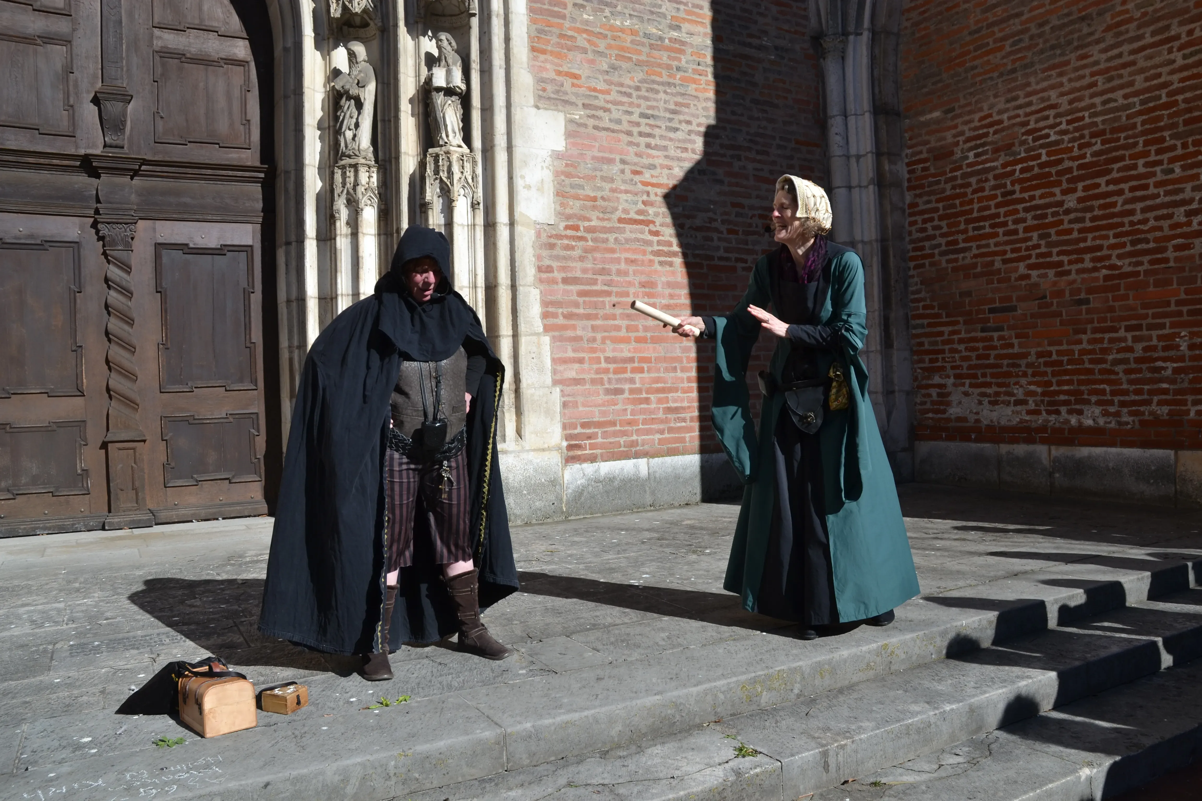 zwei mittelalterlich verkleidete Frauen vor einem alten Backsteingebäude kommunizieren.