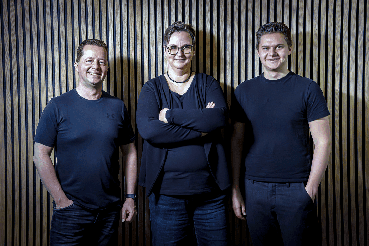 Drei Mwnschen stehen vor einer Holzwand