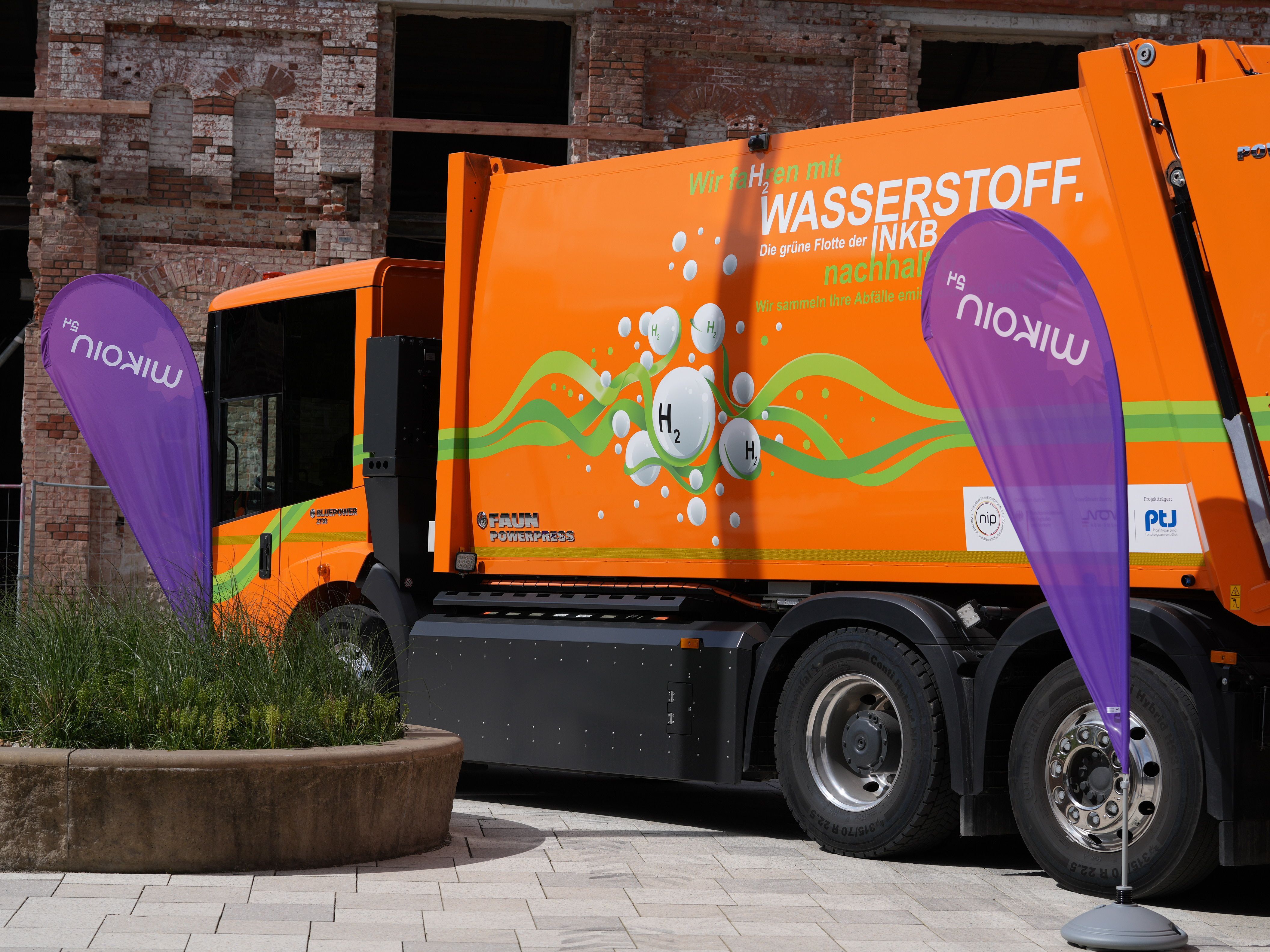 Wasserstoff-Müllfahrzeug vor MKKD-Baustelle neben WIKOIN Beachflags